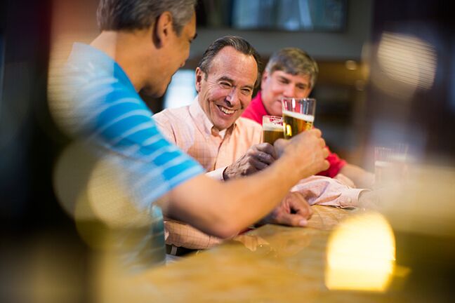 3 Men smiling clicking their beer glasses together