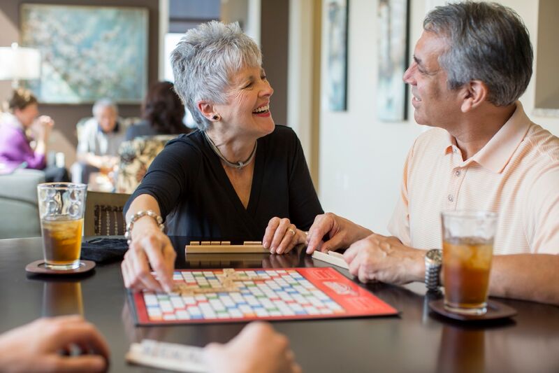 A man and a woman playing scrabble at a table with ice tea