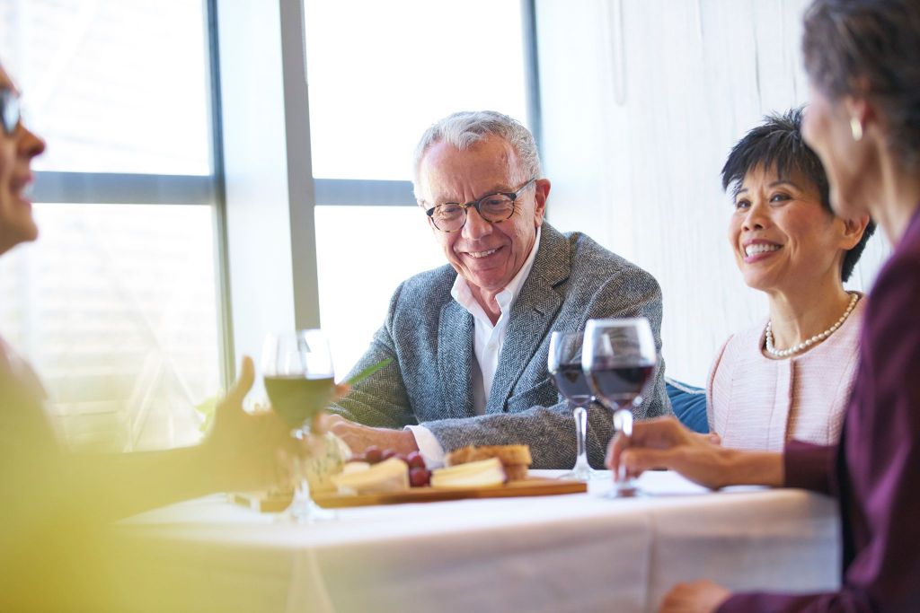 couple sitting drinking red wine at table with cheese plate