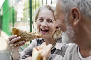 couple sitting together with woman eating a piece of pizza