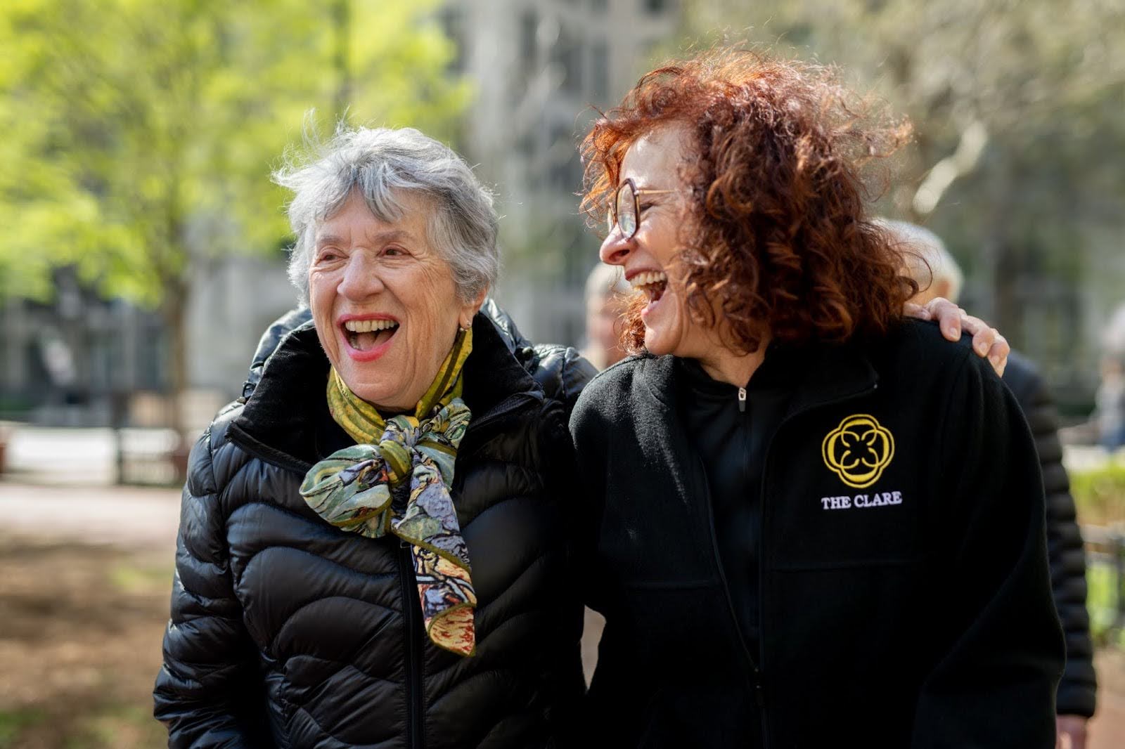 Two senior women laughing outdoors at The Clare