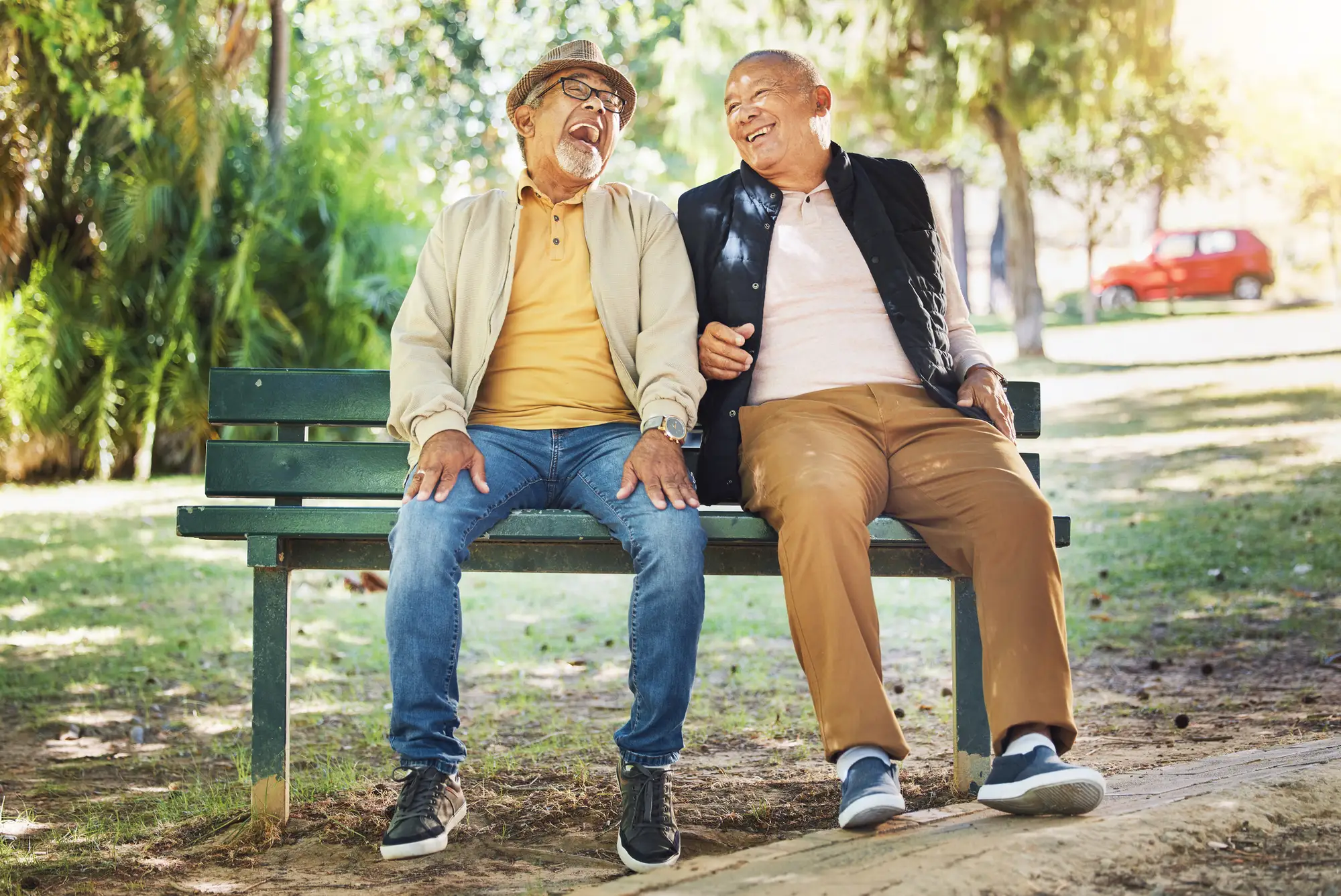 Senior men laughing on park bench after discussing senior independent living explained.